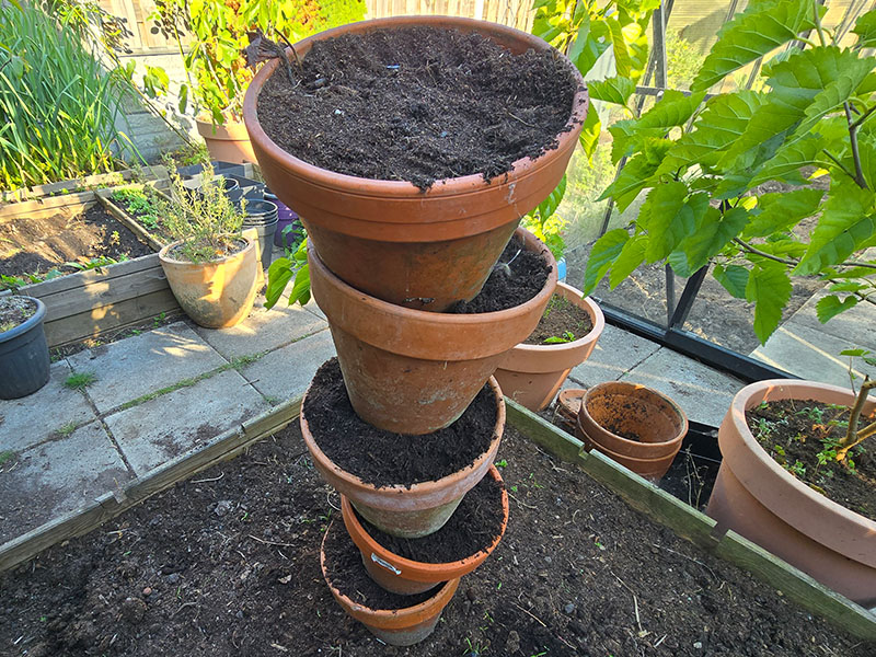 terracotta kruidentoren afgerond, gestapelde aardewerk bloempotten over betonijzer voor het maken van je eigen plantentoren voor kruiden